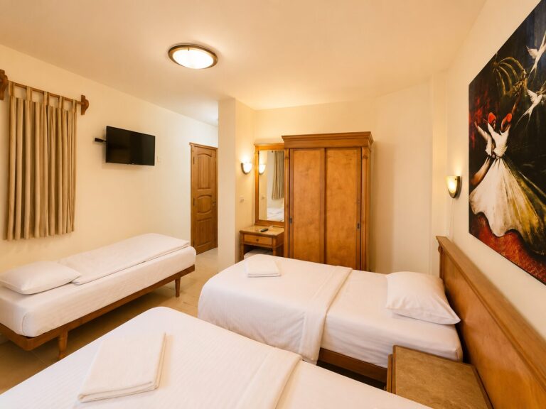 Triple sea view room with three single beds, wardrobe, TV, and Sufi artwork at Dyarna Hotel Dahab