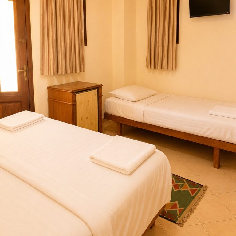 Two single beds with TV, mini fridge, and striped curtains in triple back view room at Dyarna Hotel Dahab