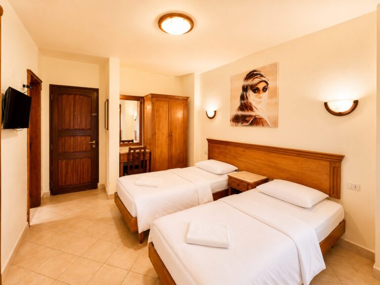 Double room with two single beds, wardrobe, TV, and Egyptian artwork at Dyarna Hotel Dahab